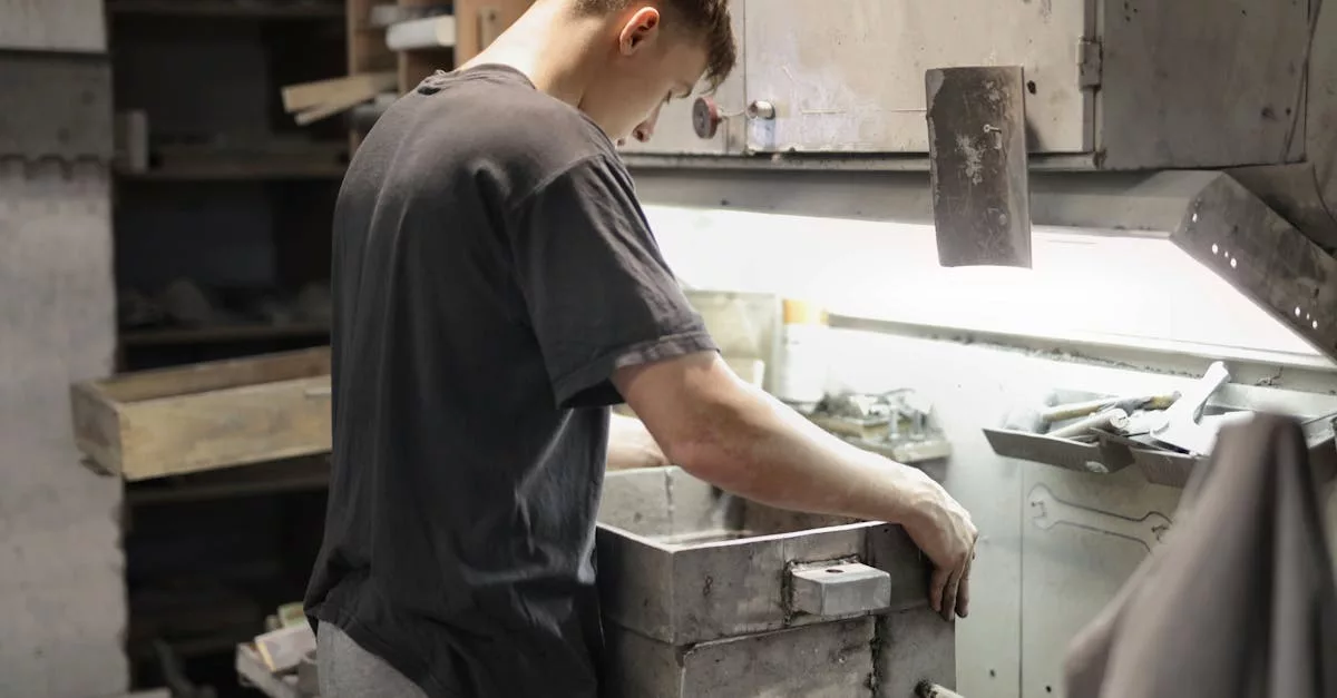 A young male craftsman focuses on metalwork in an industrial workshop.