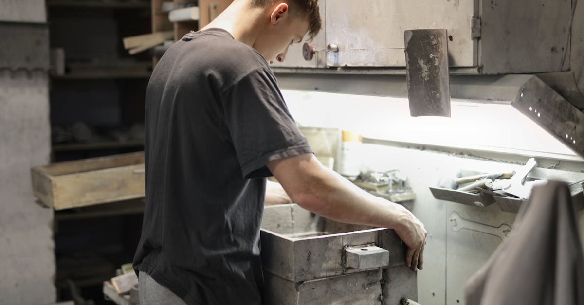 A young male craftsman focuses on metalwork in an industrial workshop.